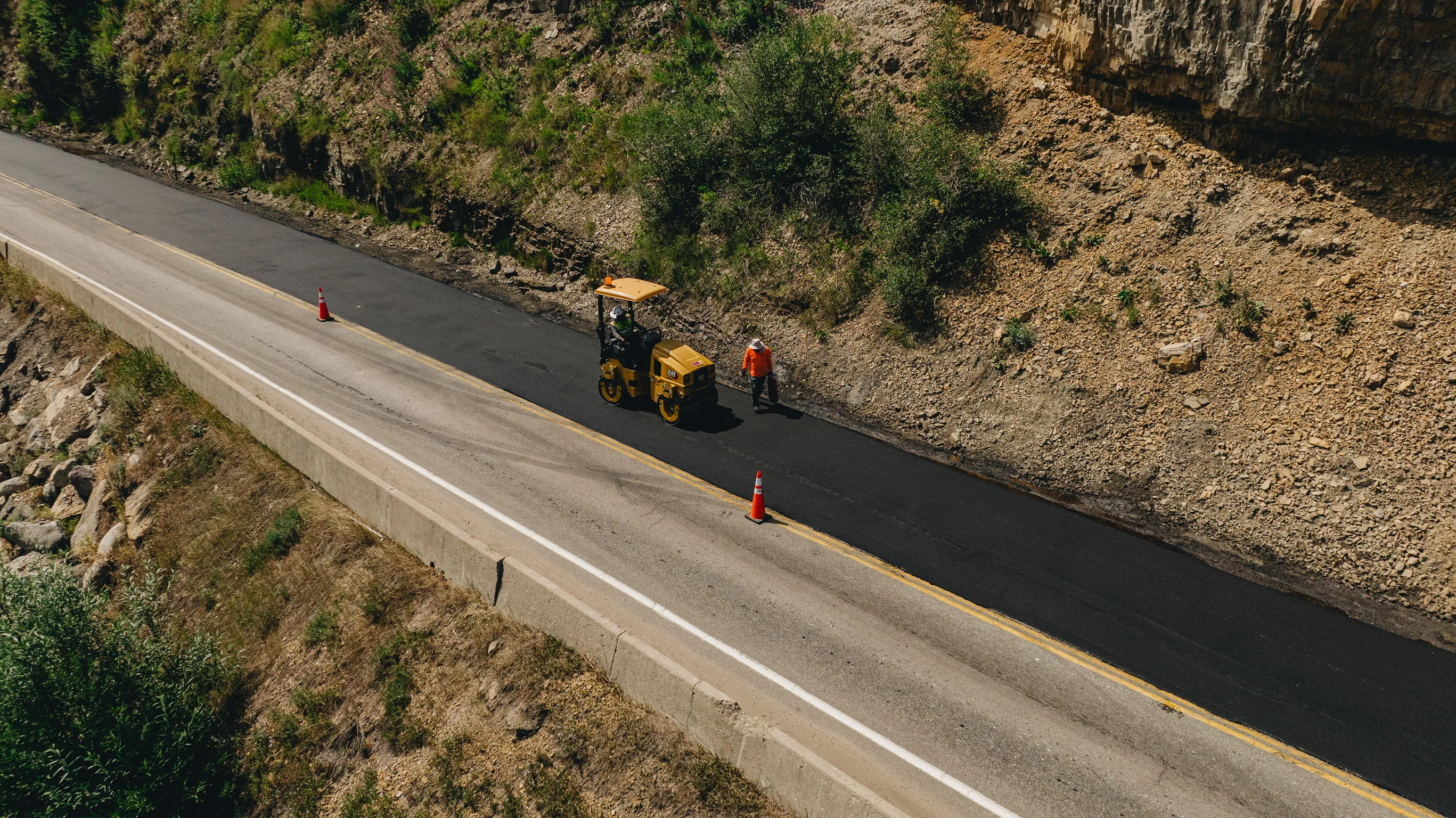 MD Asphalt roller finishing a new blacktop lane along a Colorado mountainside
